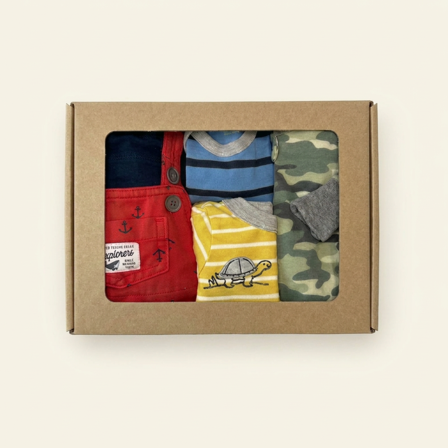 Box of children's clothing with red overalls, blue shirt, yellow shirt, and camouflage shirt.