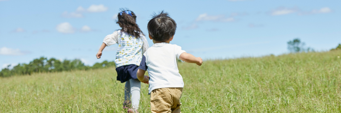 Children running in a field with blue skies