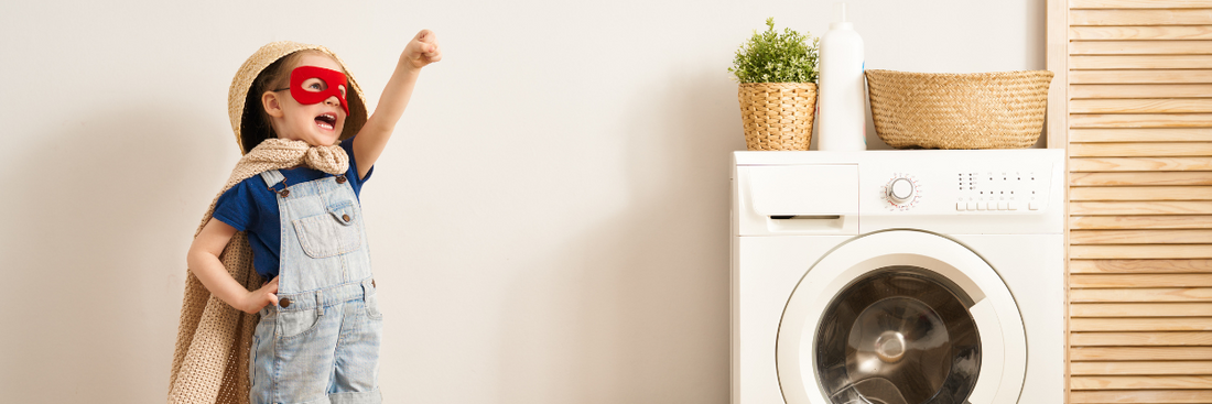 Boy dressed as superhero standing near washing machine