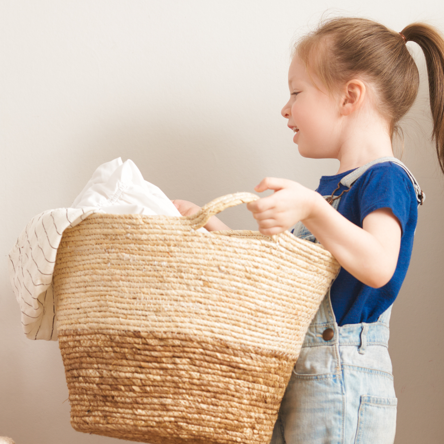 Child holding a woven basket with clothing inside 