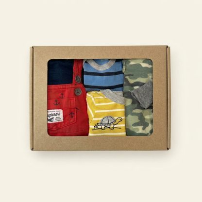 Box of children's clothing with red overalls, blue shirt, yellow shirt, and camouflage shirt.